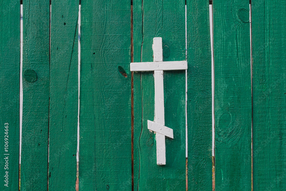 White cross on green wooden fence. Religion