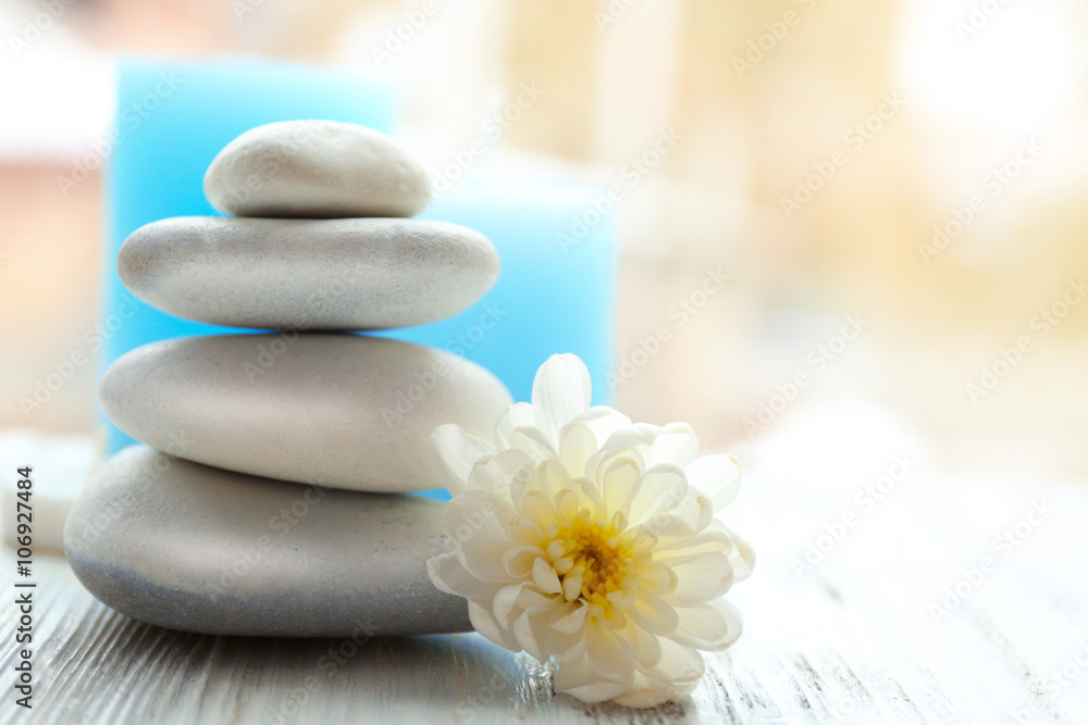 Spa stones with beautiful flower and candles on white wooden table Spa stones with beautiful flower and candles on white wooden table