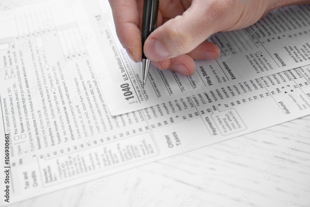 Man filling American form of Individual Income Tax Return at the table Man filling American form of Individual Income Tax Return at the table