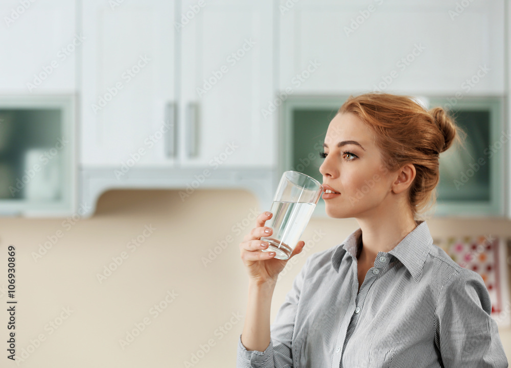 Young woman in the kitchen drinking water Young woman in the kitchen drinking water