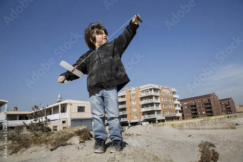 Boy at the coast preparing to fly toy airplane, Long Beach, New York State, USA photo