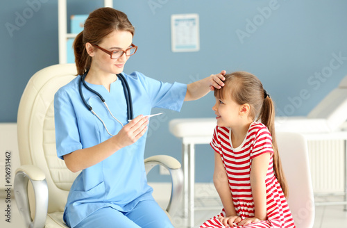 Doctor checking little girl's temperature