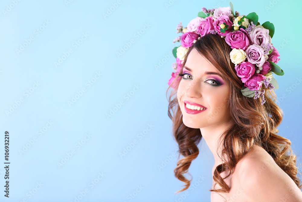 Beautiful young woman wearing floral headband on a blue background Beautiful young woman wearing floral headband on a blue background