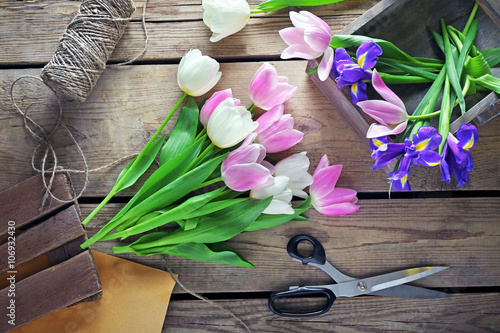 Fototapeta Naklejka Na Ścianę i Meble -  Pink, white tulips, purple irises with scissors on wooden background