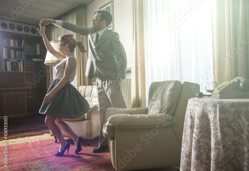 Young vintage couple dancing rock n roll in sitting room photo