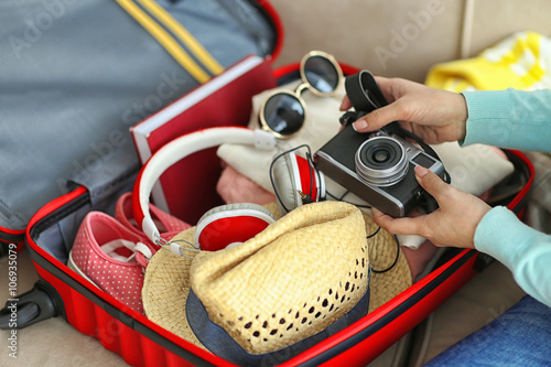 Woman packing her red suitcase, close up