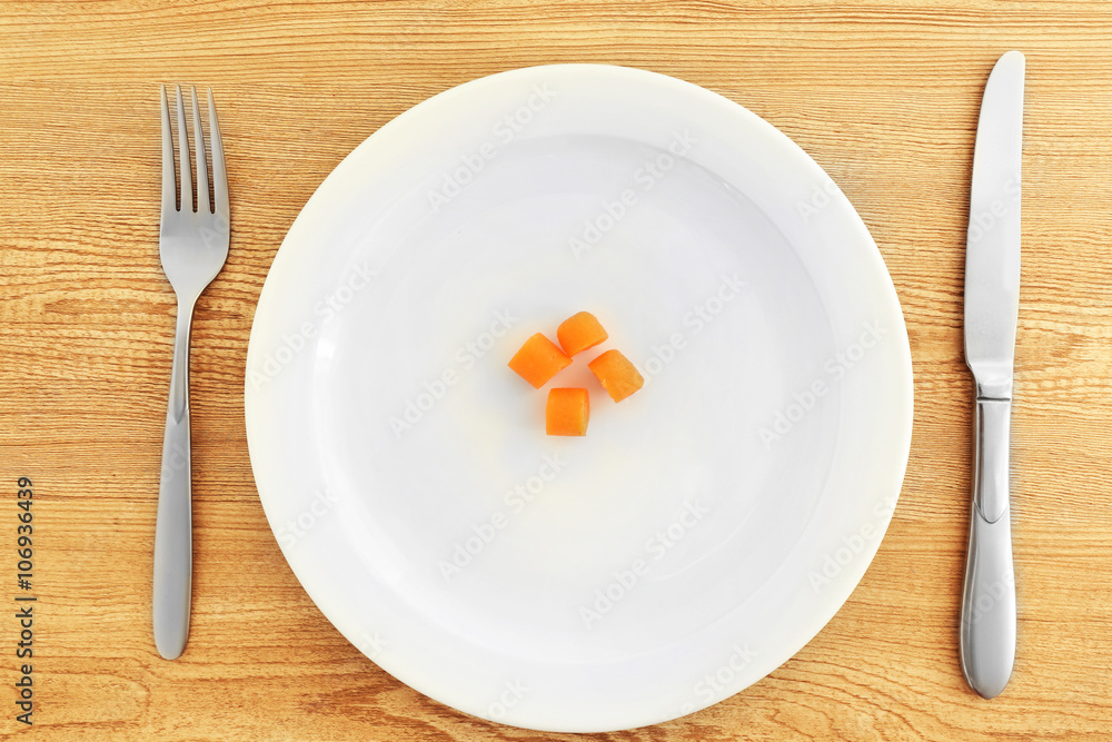 White plate with carrots on wooden background White plate with carrots on wooden background