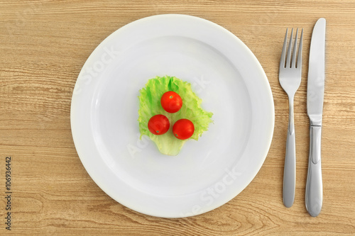 White plate with salad and cherry tomatoes on wooden background