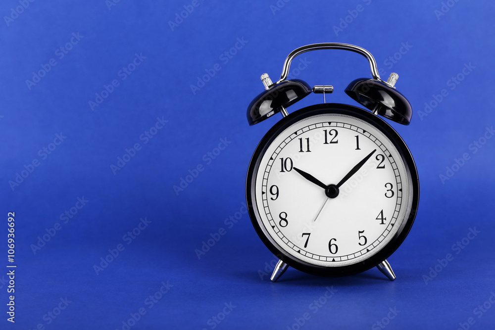 Black retro alarm clock on blue background Black retro alarm clock on blue background