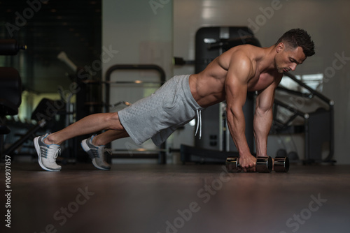 Young Man Doing Push Ups With Dumbbells On Floor