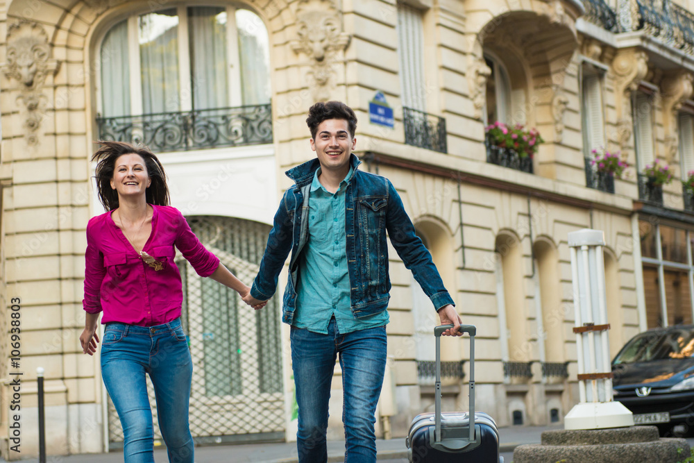 Young couple walking with wheeled suitcase, Paris, France Young couple walking with wheeled suitcase, Paris, France