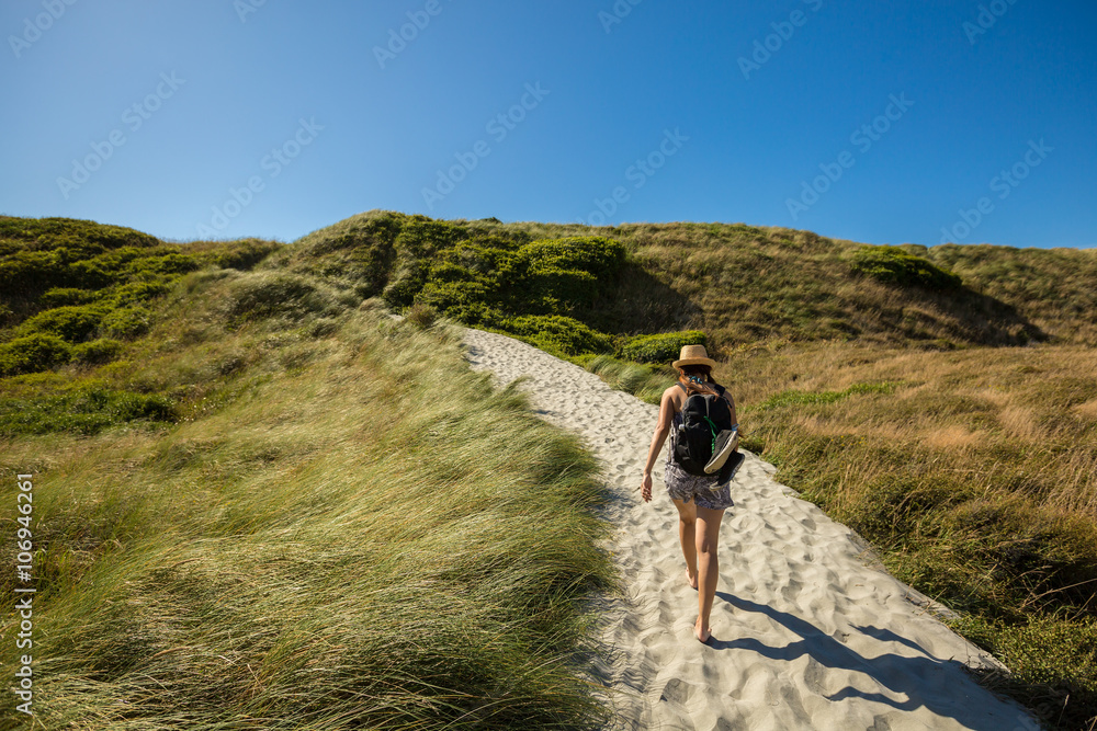young adult woman walking on sand track at Wharariki Beach