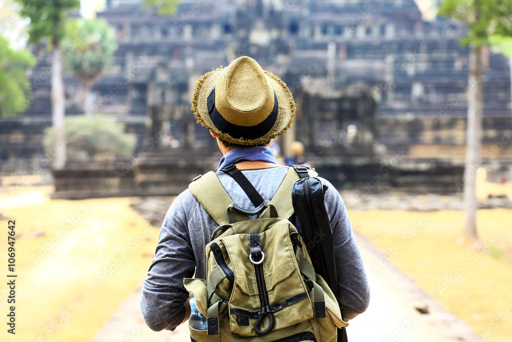 Young traveler wearing a hat with backpack and tripod - at Angkor Wat, Siem Reap, Cambodia Young traveler wearing a hat with backpack and tripod - at Angkor Wat, Siem Reap, Cambodia