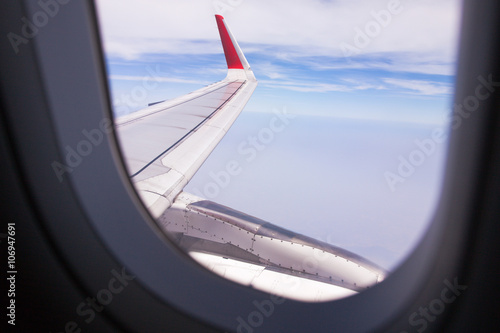Looing at clouds and blue sky through window of an aircraft