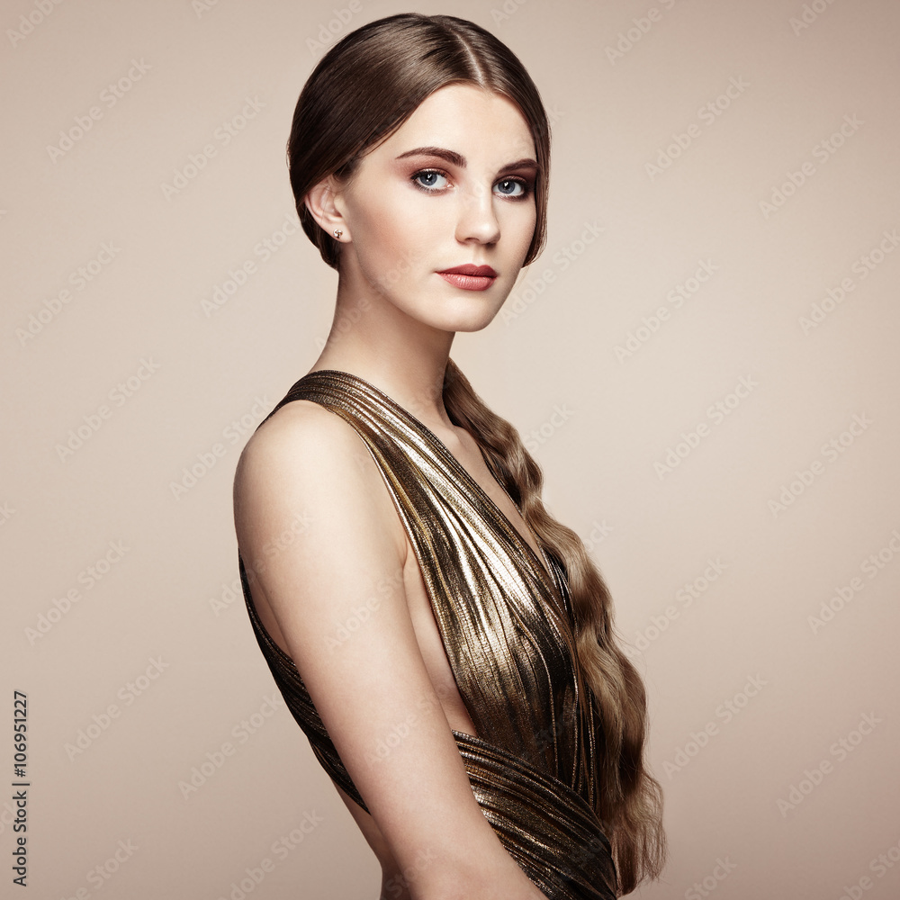 Fototapeta premium Fashion portrain of young beautiful woman in gold dress. Brunette glamour lady with perfect make up and hairstyle