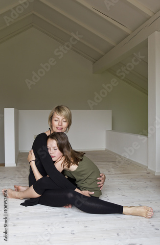 Mother and twelve year old daughter hugging on floor photo