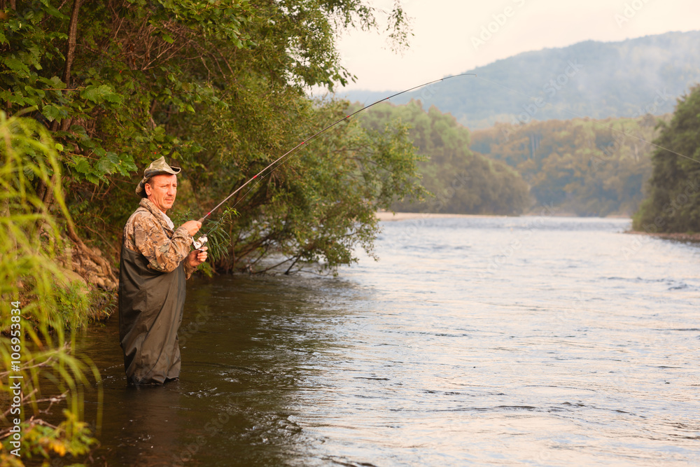 Fisherman on a mountain river catches of pink salmon Fisherman on a mountain river catches of pink salmon
