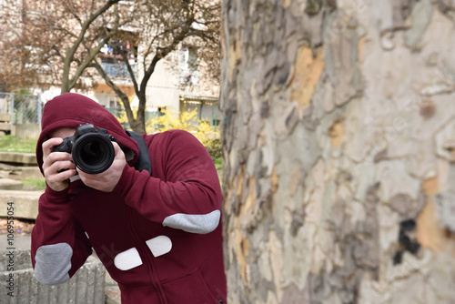 Quadro em tela Mysterious paparazzi photographer with the hood on his head lurking behind the t