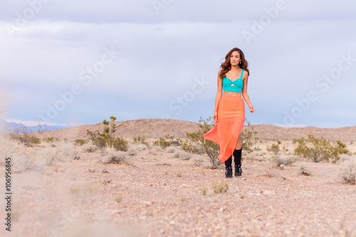 Attractive fashionable young woman in the desert walking in pink skirt