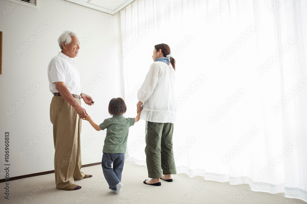 Three generation family standing by window holding hands Three generation family standing by window holding hands