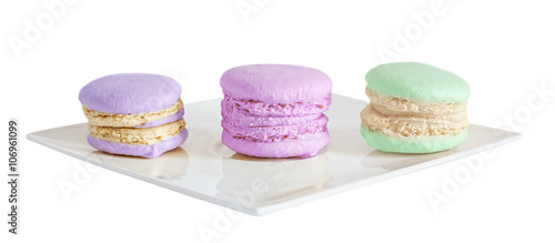 Multi colored sweet macaroons, french traditional, cream, white plate, close up, isolated on a white background