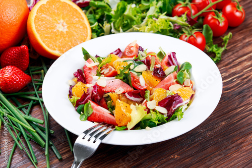 Fresh Orange, strawberry vegetables salad. on wooden table.