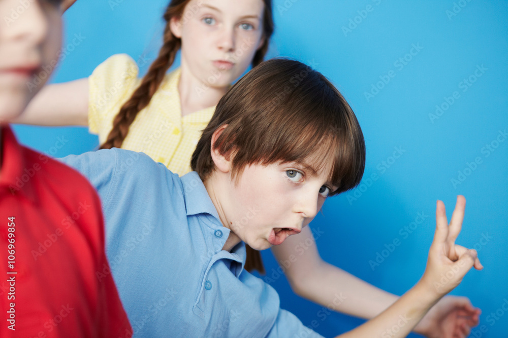 Three children against blue background, boy making peace sign Three children against blue background, boy making peace sign
