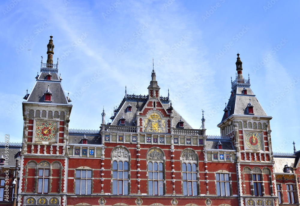 Amsterdam Centraal Station. Building exterior of Amsterdam Centraal and blue sky with flying seagull. Capital city of the Netherlands, central station or metro station.