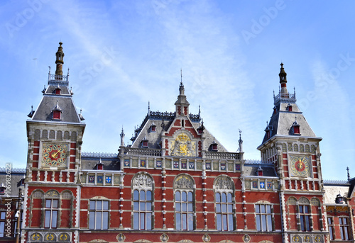 Amsterdam Centraal Station. Building exterior of Amsterdam Centraal and blue sky with flying seagull. Capital city of the Netherlands, central station or metro station.
