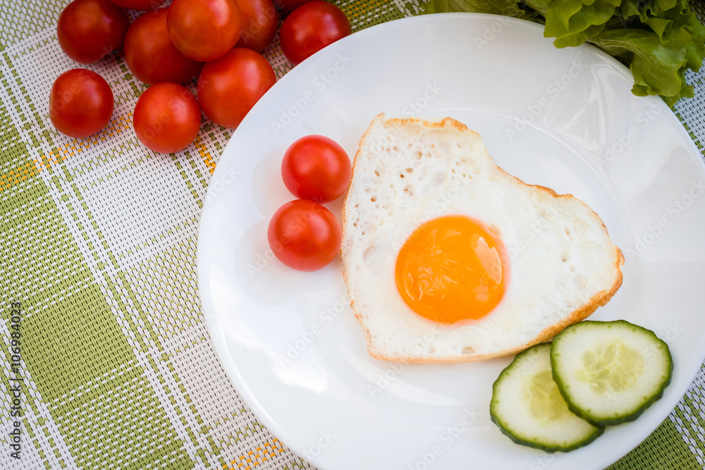 Fried egg in heart shape with vegetables