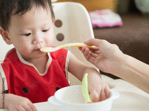 Asian toddler eat meal herself.