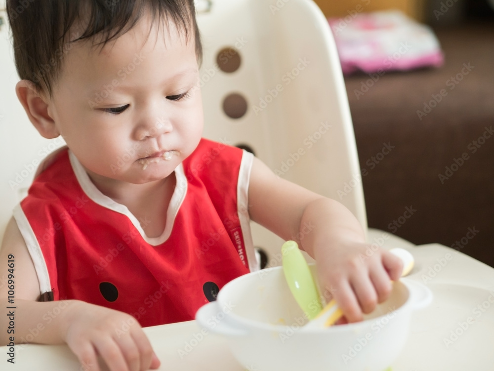Asian toddler eat meal herself. Asian toddler eat meal herself.