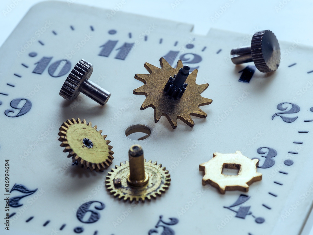 Dismantled clock mechanism. Gears of golden metal can be seen in the  complex mechanism. Brass gear lie on the disassembled hours. The complex  mechanism of small size. Inside the clock. Stock Photo