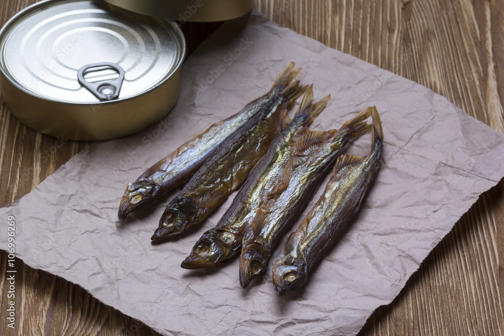 Smoked capelin and conserve tins on wooden background Smoked capelin and conserve tins on wooden background