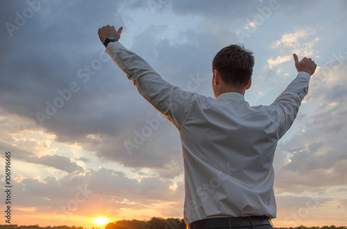 happy businessman standing in field with his thumbs up