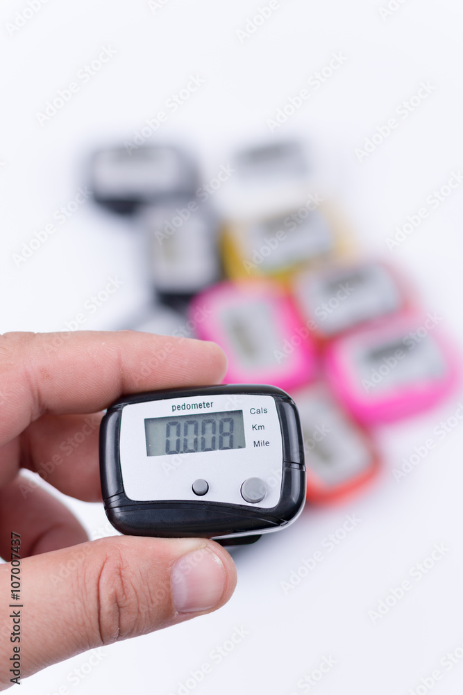 Digital pedometer in the hand over pile of pedometers Stock Photo