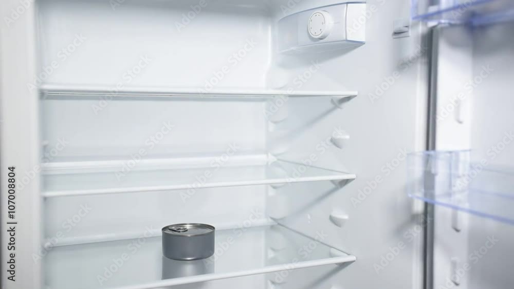 Fridge door opening and closing with one can inside. Nothing to eat. Diet and hunger concept. Fridge door opening and closing with one can inside. Nothing to eat. Diet and hunger concept.