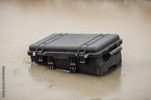 Closed plastic protector case lying  on the water and dirt photo