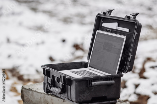 Opened plastic protector case with laptop lying  on a construction photo