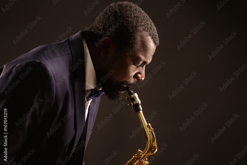 Naklejka premium African American jazz musician playing the saxophone on grey background