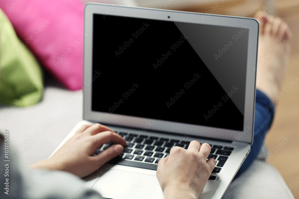 Woman sitting on sofa with a laptop in a room Woman sitting on sofa with a laptop in a room