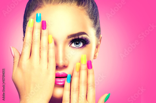 Valokuvatapetti Beauty girl face with colorful nail polish