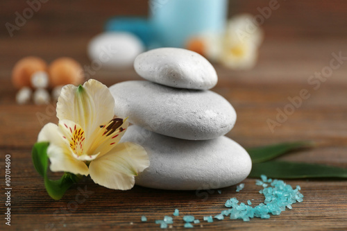 Spa still life with flowers and stones on wooden table closeup