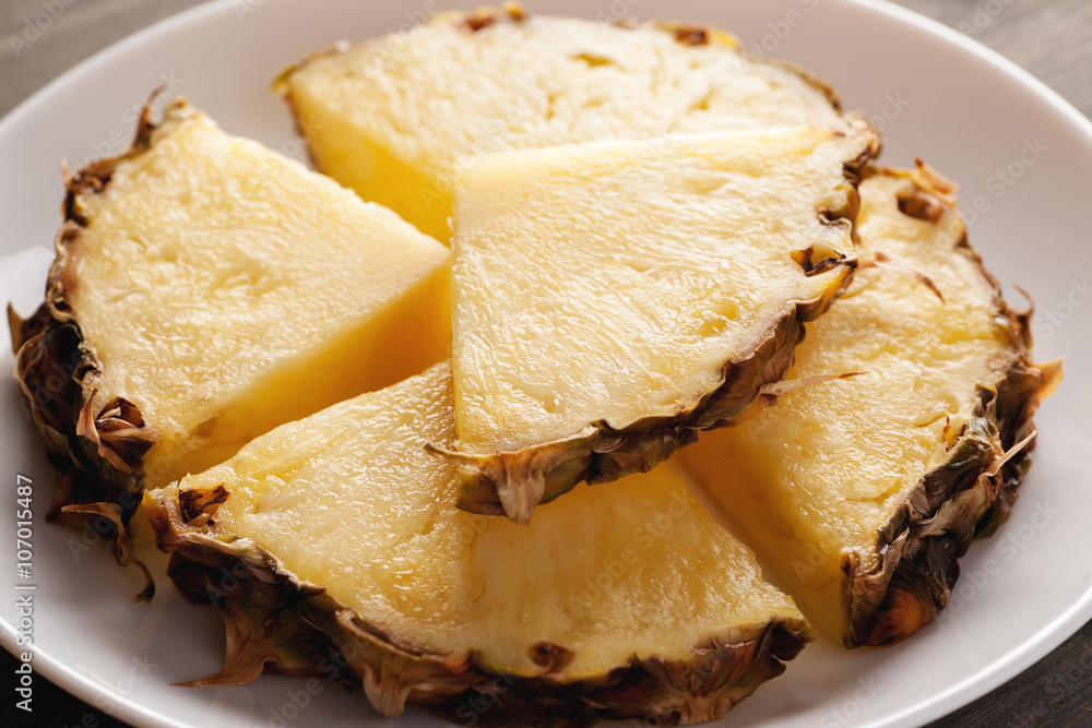 Sliced pineapple with peel on a white plate
