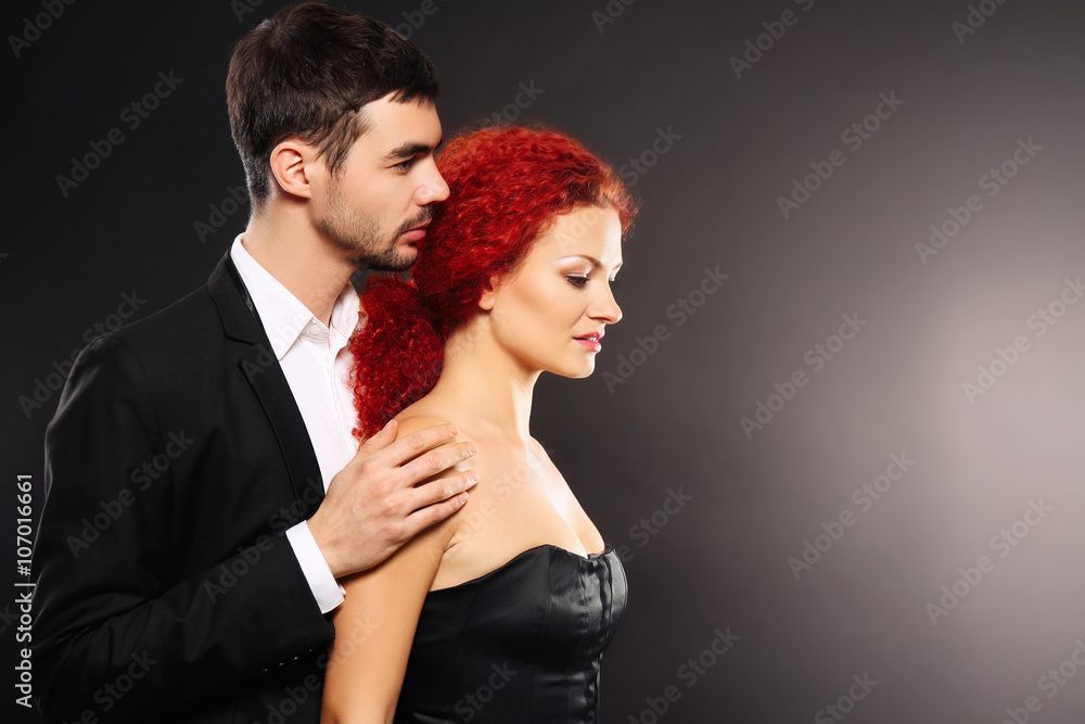 Young couple in dress and suit standing together on black background Young couple in dress and suit standing together on black background