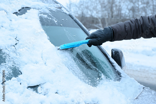 Removing snow from car windshield, closeup