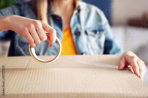 Εκτύπωση καμβά Young girl sealing with tape big cardboard box for moving