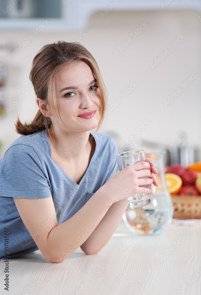 Young woman drinking water from glass in the kitchen Young woman drinking water from glass in the kitchen