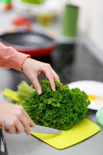 Female hands cut parsley on desk, closeup