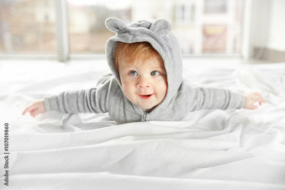 Little baby boy in grey pajamas lying on the bed, close up Little baby boy in grey pajamas lying on the bed, close up